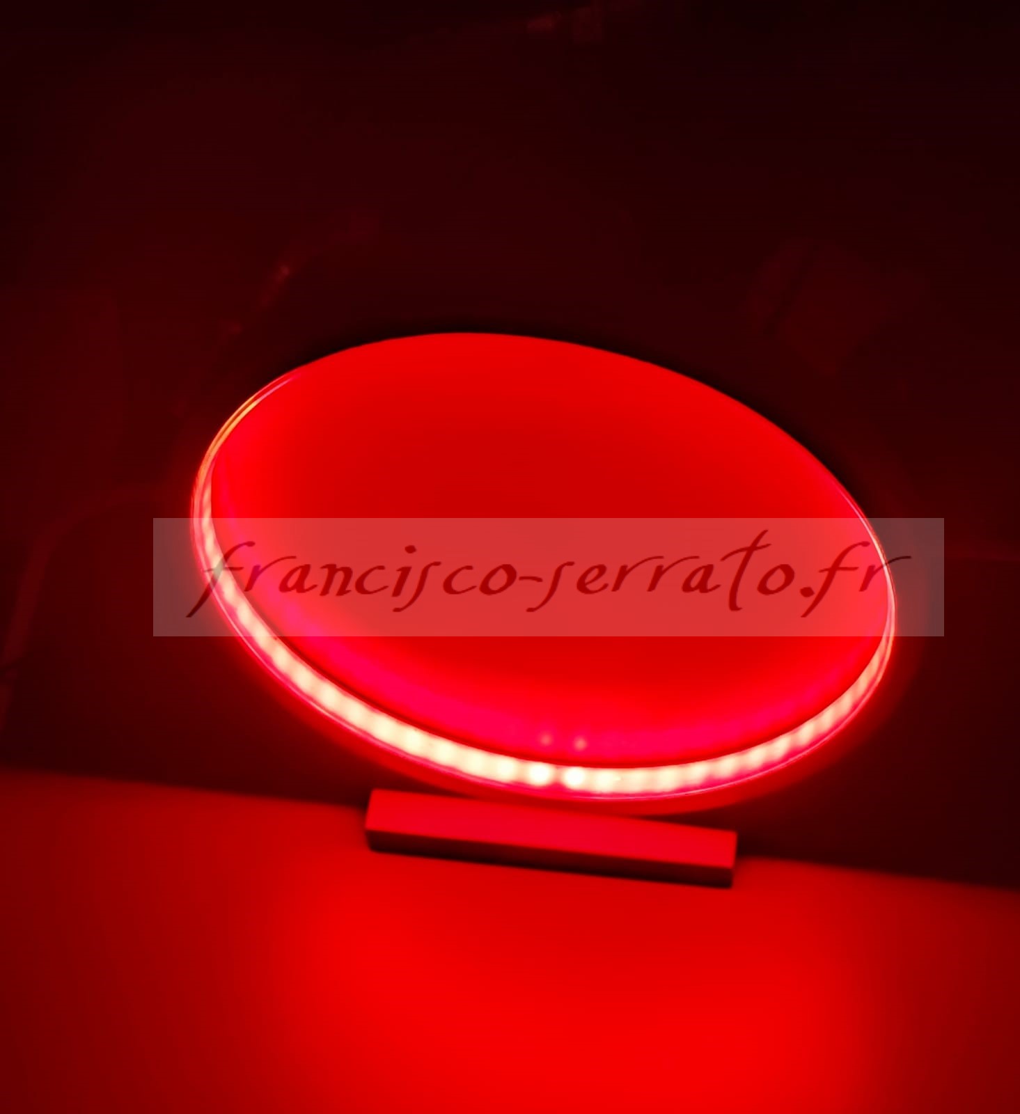 Un ruban led et un miroir peint compose cette lampe ronde de couleur rouge métallisé